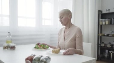 Sebze salatasına, tatlı keke, kilo verme diyetine bakan kafası karışmış bir kadın.