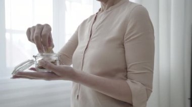 Olgun bir kadın fındık yiyor, sağlıklı atıştırmalıkların tadını çıkarıyor, dengeli diyet yapıyor, sağlık hizmeti veriyor.