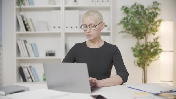 オフィスのノートパソコン上の深刻なビジネス女性の仕上げプロジェクト 仕事の日の終わり — ストック動画
