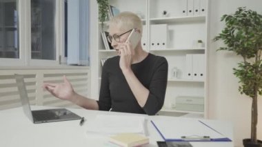 Birden fazla iş kadını telefonda konuşuyor, belgeleri kontrol ediyor, işte meşgul.