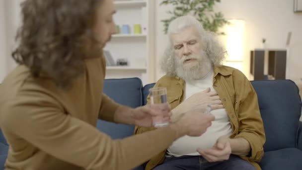 Пожилой Человек Страдающий Боли Груди Отвергающий Лекарства Воду Заботливого Сына — стоковое видео
