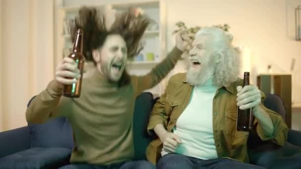 Szczęśliwy Syn Ojciec Butelkami Piwa Oglądając Piłkę Nożną Telewizji Świętując — Wideo stockowe