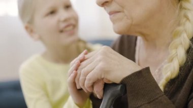 Sevgi dolu torun engelli büyükannenin elini tutuyor, baston, destek ve özenle.