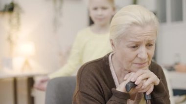 Sevimli küçük kız üzgün büyükannene bastonla sarılıyor, aile desteği, engelliler...