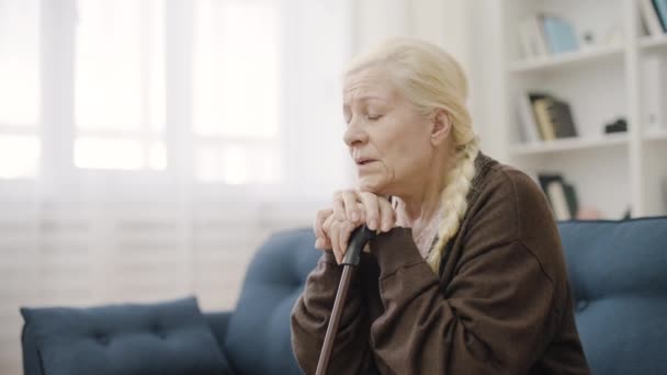 Расстроенная Зрелая Женщина Тростью Сидящая Диване Одна Ослабленное Здоровье — стоковое видео