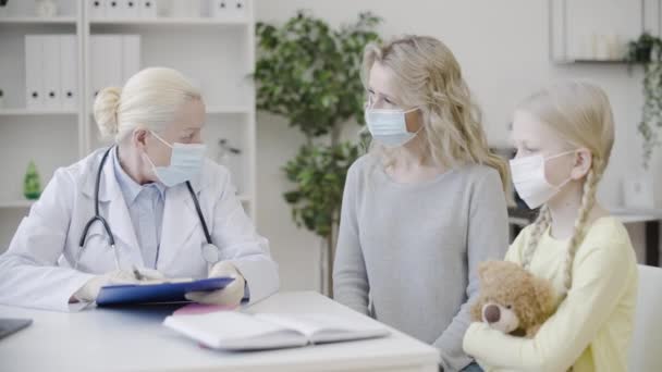 Vrouw Kind Maskers Doktersconsult Moeder Vult Medisch Formulier — Stockvideo