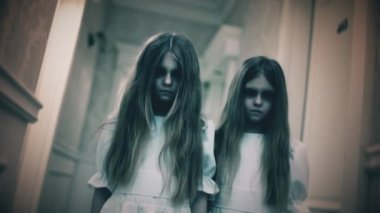 Solgun yüzlü ve boş gözlü iki ürkütücü küçük kız kameraya bakıyor, korku. Paranormal olaylar, hayalet aktiviteleri, korku sahneleri.