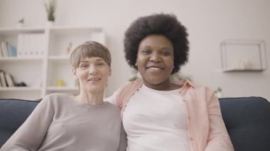 Mutlu Afrikalı ve Kafkasyalı kadınlar kameraya el sallıyor, video görüşmesi yapıyorlar.