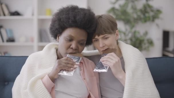 Zwei Depressive Freundinnen Essen Schokoriegel Auf Der Couch Stress Abzubauen — Stockvideo