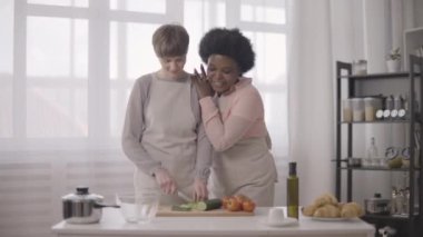 Aynı cinsiyetten romantik bir çift birlikte yemek pişiriyor, mutfakta hobi ediniyor.