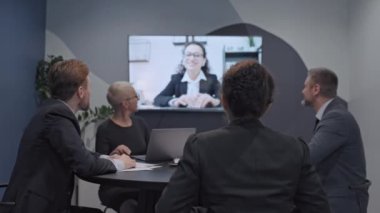 Şirket çalışanları patronla konferans görüşmesi yapıyor, proje görevlerini tartışıyorlar.