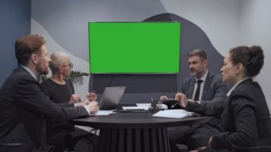 İş danışmanlığı ekibi yeşil ekrana bakıyor, projeyi tartışıyor, takım çalışması
