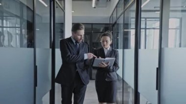 Erkek patron, yürüyen ofis koridorundaki kadın sekretere iş talimatı veriyor.