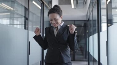 Yavaş hareket eden neşeli iş kadını ofise atlıyor, başarılı bir anlaşmayla mutlu.