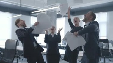 Başarılı iş adamları kağıtları havaya atıyor. Yavaş çekimde, zaferle mutlu.