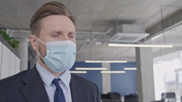 Nieszczęśliwy Biznesmen Masce Medycznej Stojący Pustym Biurze Kryzys Pandemiczny — Wideo stockowe