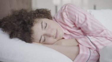 Genç, rahat bir kadın, rahat bir yatakta zevkle uyanıyor, hayatın tadını çıkarıyor.