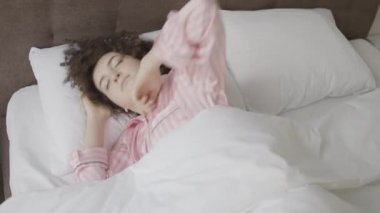 Kadın rahat bir yatakta zevkle uyanıyor, rahat bir uyku, hayatın tadını çıkarıyor.