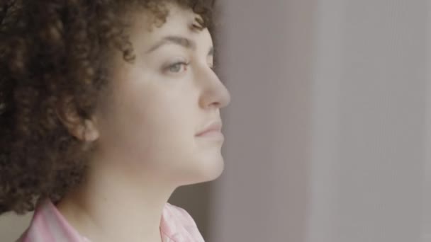 Üzgün Kıvırcık Saçlı Kadın Sabahları Pencereden Dışarı Bakıyor Sorunu Düşünüyor — Stok video