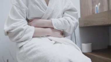 Karın ağrısı çeken, banyoda endometriyoz geçiren bir kadın.