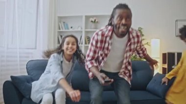 Mutlu Afrikalı baba ve kızları kanepede oturup televizyon seyrediyorlar.