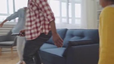 Komik Afro-Amerikan kızları ve babaları kanepede oturup televizyon izliyorlar.