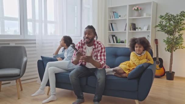 Anak Perempuan Bosan Duduk Sofa Sementara Ayah Dengan Antusias Menonton — Stok Video