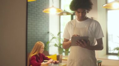 Sipariş almak için tablet kullanan garson, restoranda dizüstü bilgisayarda çalışan müşteri.