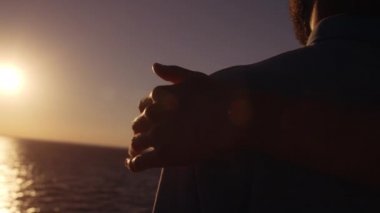 Erkek eli yaklaş. Deniz kenarında genç adama nazikçe sarıl, destek ol.