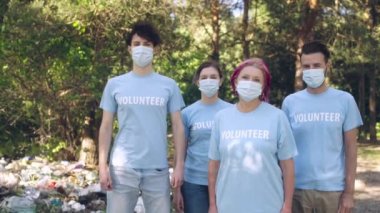 Yüz maskeli ekoloji aktivistleri parktaki çöp yığınının yanında, doğal afet.