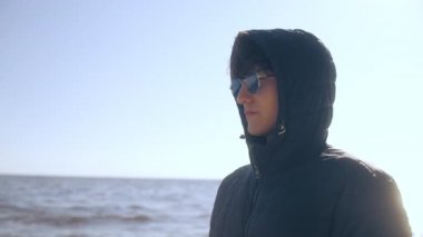 Düşünceli genç adam sonbaharda soğuk deniz suyuna bakıyor, yalnızlık çekiyor.