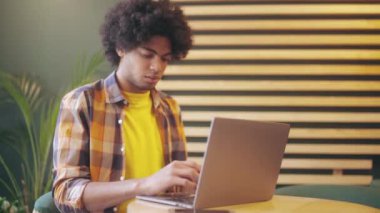 Kafede dizüstü bilgisayarda çalışan melez genç adam, serbest meslek, uzaktan eğitim