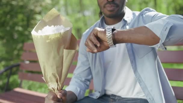 Afrikaner Überprüft Seine Uhr Und Wartet Mit Einem Blumenstrauß Auf — Stockvideo