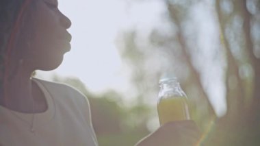 Mutlu Afro-Amerikalı kadın dışarıda portakal suyu içiyor, sağlıklı içecek.