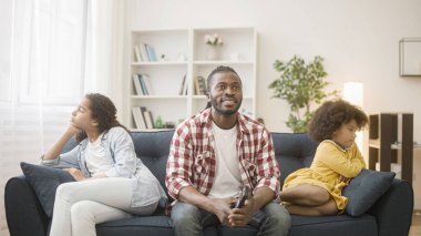 Babam futbol seyrediyor ve kırgın kızları görmezden geliyor. Ayrı ayrı kanepede oturuyorlar.