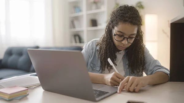Saçları afro saçlı gençler dizüstü bilgisayarda ödev yapıyor, notlar alıyor, uzaktan öğreniyor.