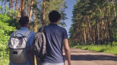 Erkek gezginler otostop çekerken başparmak hareketi yapıyor, arkadaşlar birlikte seyahat ediyor.