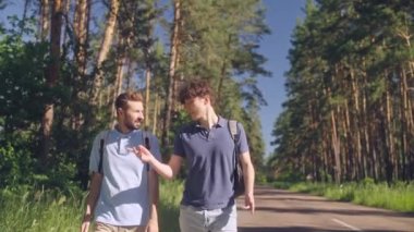 Otobanda otostopçu jesti yapan iki erkek arkadaş.