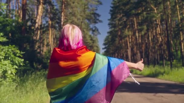 Kobieta Owinięta Flagę Lgbt Wykonująca Gest Kciuka Autostopowicza Drodze Parada — Wideo stockowe