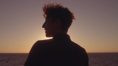 Rahat genç adam deniz üzerinde gündoğumunun tadını çıkarıyor, lüks bir gemi gezisinde dinleniyor.