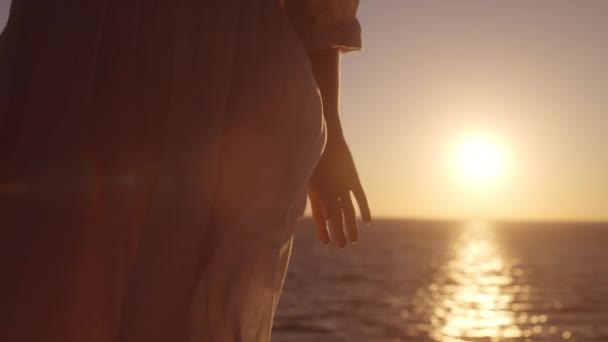 美しい白いガウンに触れる女性の女性 夜明けに潮風を楽しんで — ストック動画