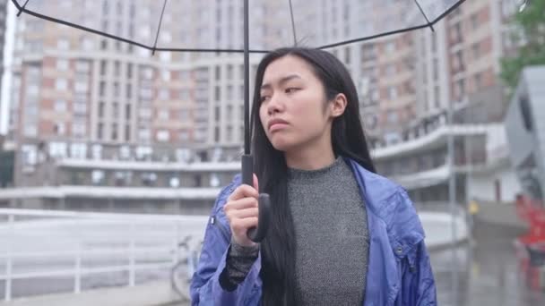悲しいアジアの女性傘の下で雨の通りを歩くと フラストレーション 計画を台無しに — ストック動画