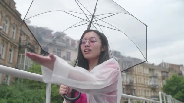 雨が降って傘を閉じて散歩に行くのを喜んでいる若いアジアの女性 — ストック動画