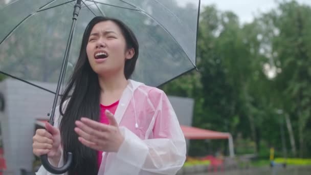 傘のくしゃみ 喉の痛み 雨の中で寒さと不幸なアジアの女性 — ストック動画