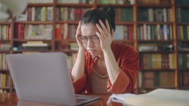 Çok çalışmaktan, stresten ve akademik baskıdan bıkmış Asyalı genç bir kadın.