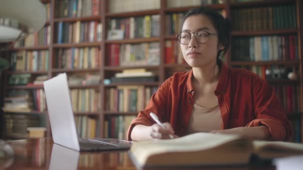Estudante Asiático Pensando Sobre Enredo Ensaio Trabalhando Com Livros Biblioteca — Vídeo de Stock