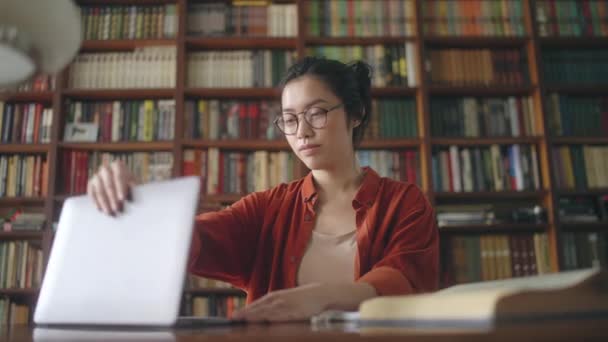 亚洲女性自由撰稿人在图书馆打开笔记本电脑 为博客写文章 — 图库视频影像