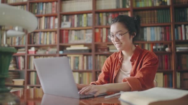 Χαρούμενη Ασιάτισσα Φοιτήτρια Τελειώνοντας Έργο Κλείνοντας Λάπτοπ Στη Βιβλιοθήκη — Αρχείο Βίντεο