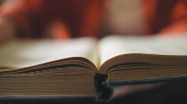 Büyük, eski bir kitap okuyan kadın, şehir kütüphanesinde araştırma yapan bir yazar, yakın plan.