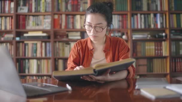 Молодая Азиатка Листающая Страницы Большой Книги Увлеченная Чтением — стоковое видео